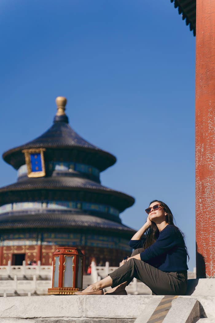 Mujer sentada con un templo de Beijing al fondo