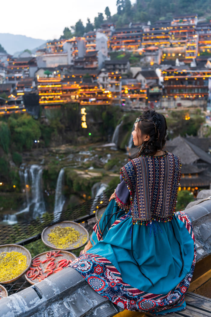 Mujer sentada viendo desde la altura la ciudad de lijiang