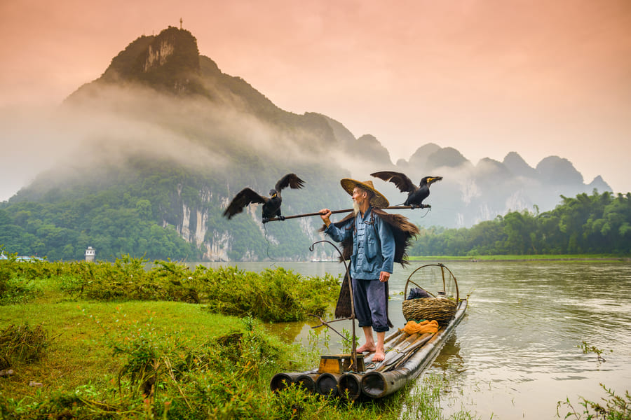 hombre pescador en lacha en el lago yangshou con montañas de fondo viajes a china