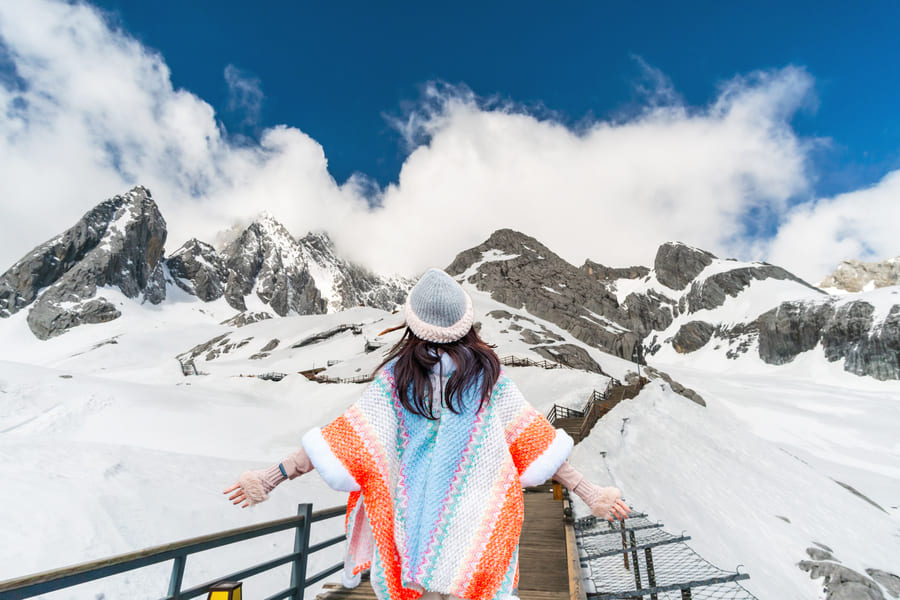 Mujer de espaaldas en las montañas nevadas de yulongshang